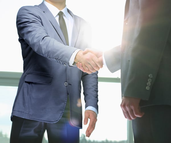 Two people shaking hands wearing suits, inbound marketing success and new clients concept. 