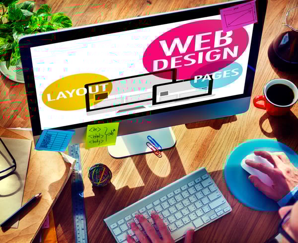 Man working on computer with Web Design, Layout, and Pages in different colored bubbles on the screen