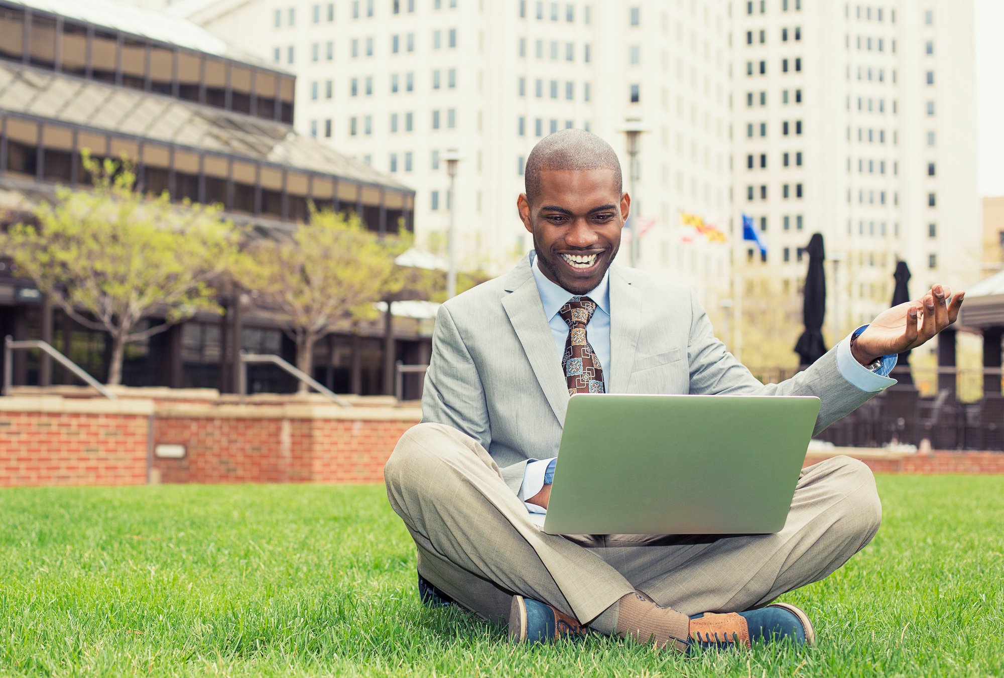 Smiling man with laptop outdoor reading good news email