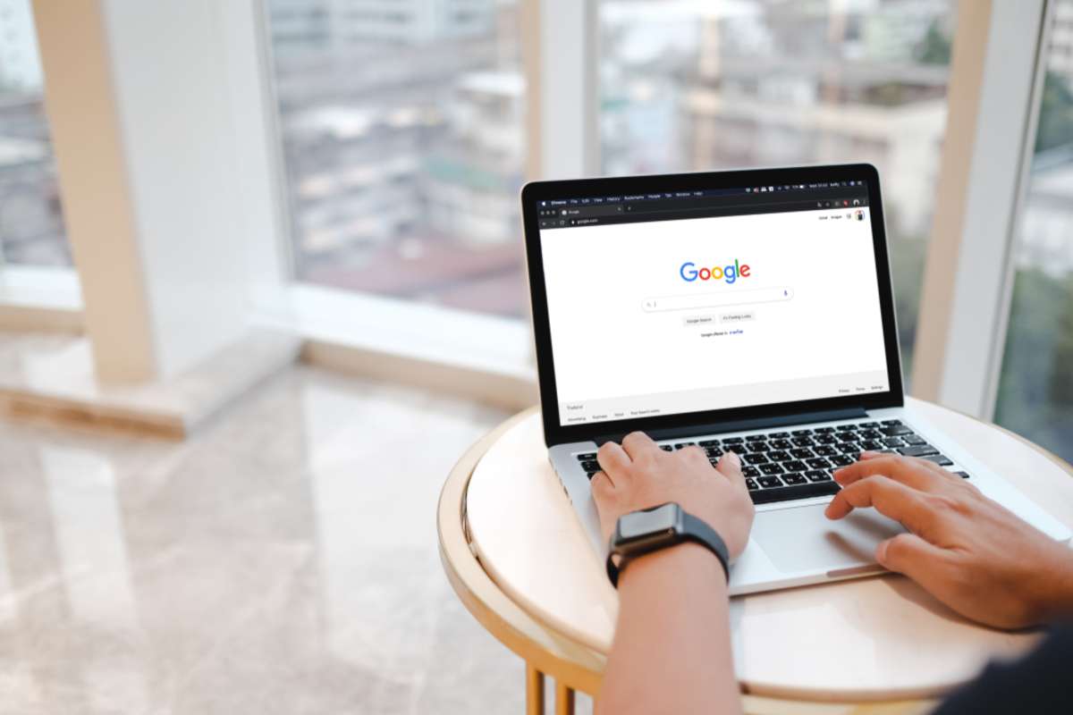 A man is typing on Google search engine from a laptop