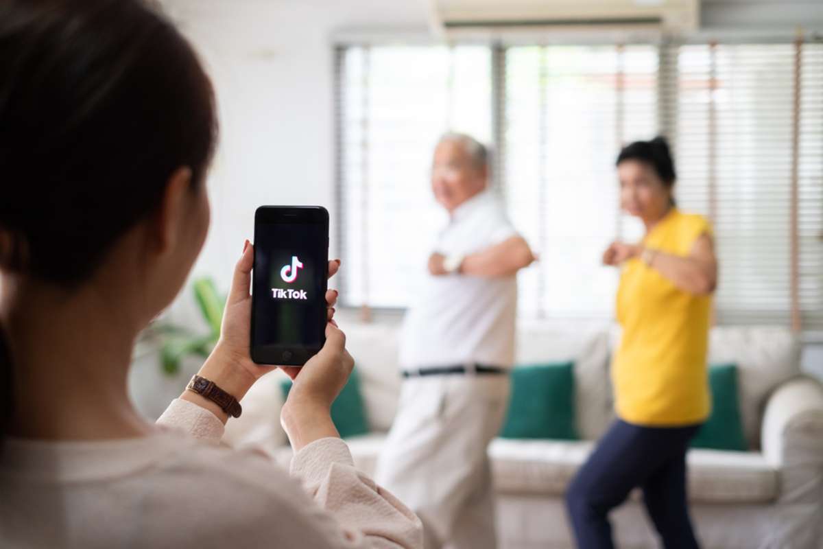 Asian woman using mobile phone take video clip of senior people dancing to share on tiktok application