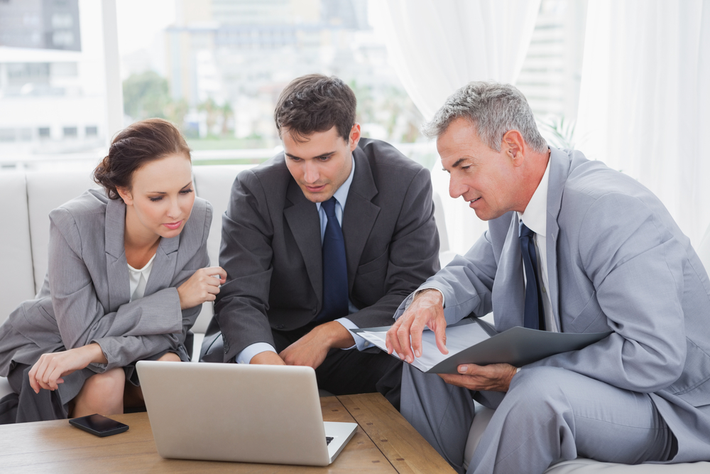 Business people working together on a laptop in a meeting room, building a property management website concept. 