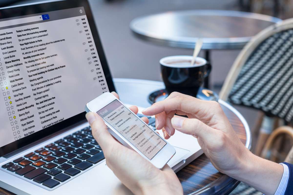 Business person reading emails on smartphone and laptop computer screen online