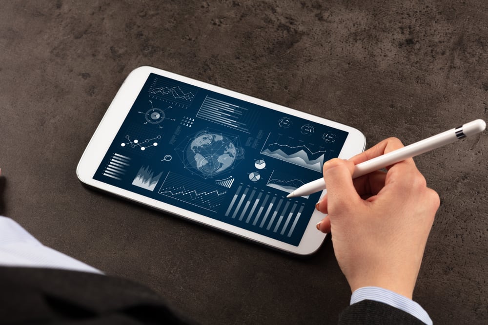 Business woman verifying reports on tablet with pencil in business suit-1