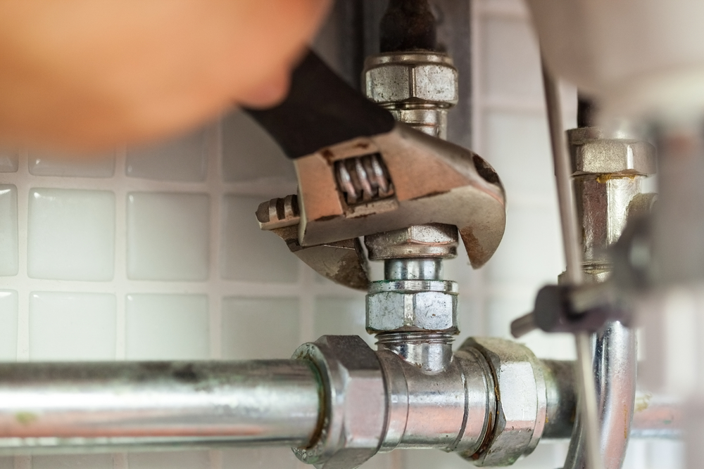 Close up of hand repairing pipes with wrench