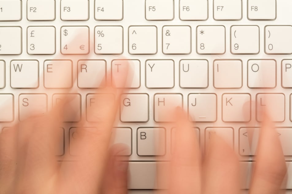 Fingers typing on a keyboard creating content for a property management blog. 