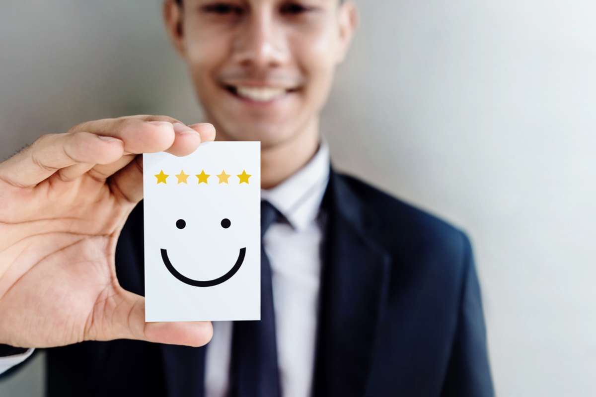 Customer Experience Concept, Happy Businessman holding Card with Smiley Face and Five Star Rating for his Satisfaction