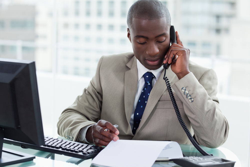 Entrepreneur making a phone call while reading a document in his office-1