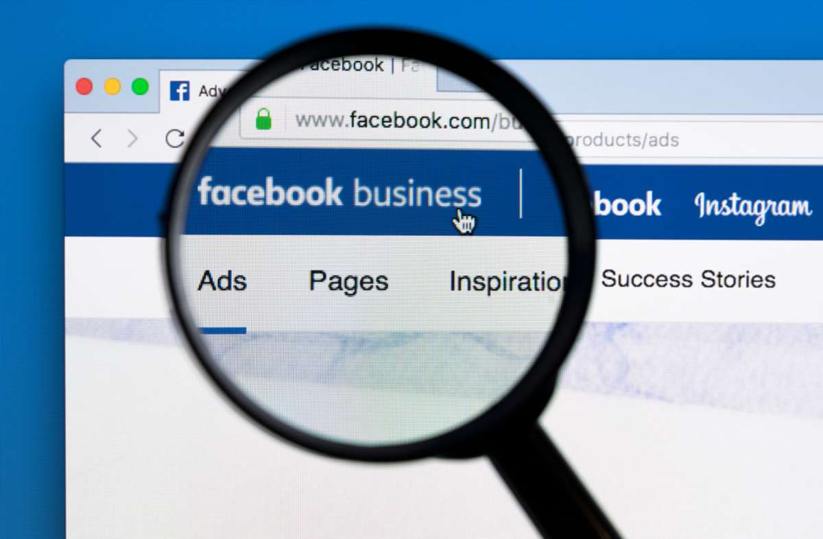 Facebook business homepage website on Apple iMac monitor screen under magnifying glass