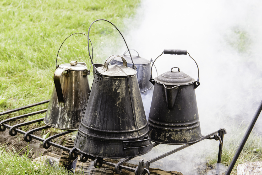 Four vintage coffeepots over a smoky campfire