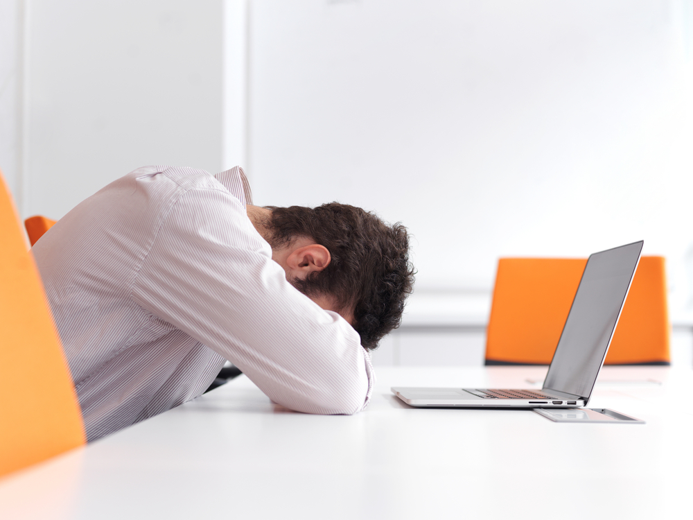 Frustrated young business man have stress problems. Sitting alone at office meeting room  and working on laptop compute.