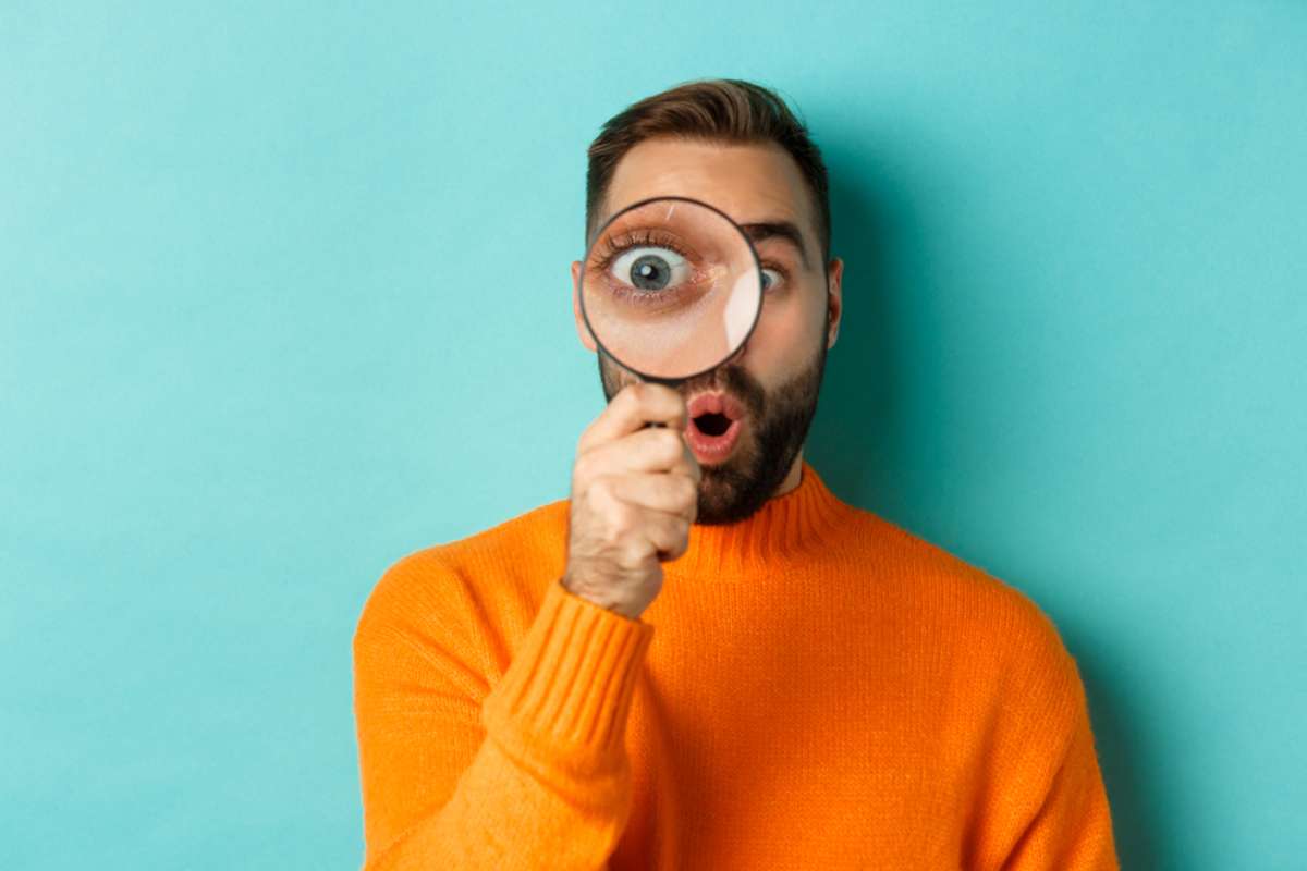Funny man looking through magnifying glass