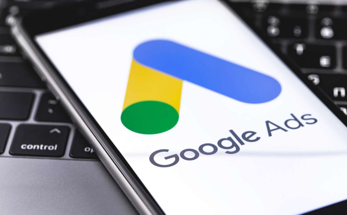 Google Ads logo on the display iPhone closeup on keyboard background