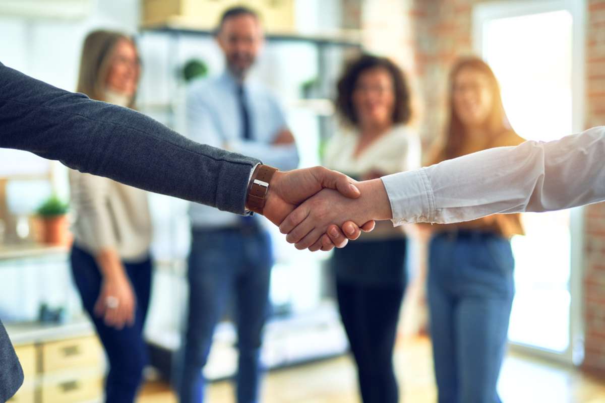 Group of business workers standing together shaking hands at the office