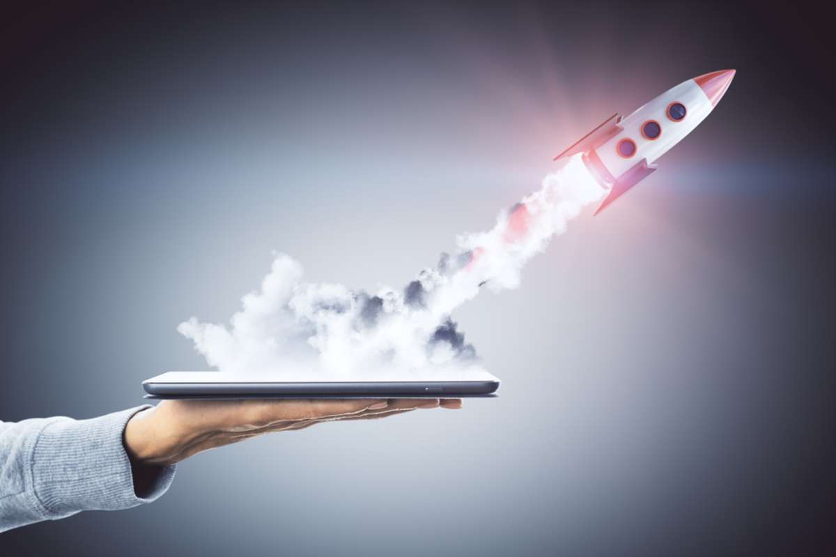 Hand holding smartphone with launching rocket on dark background
