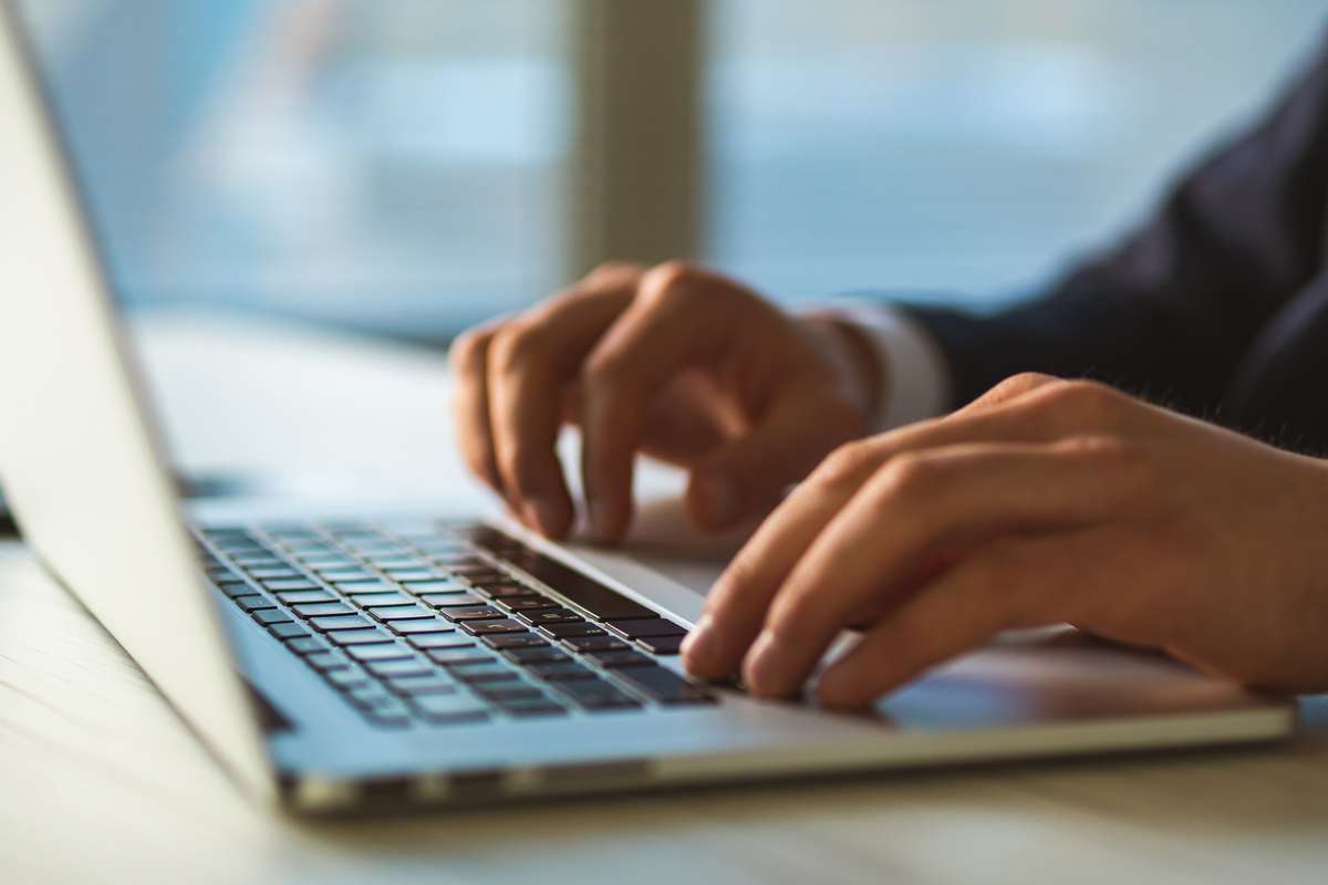 Close-up of hands typing on laptop, property management blog concept