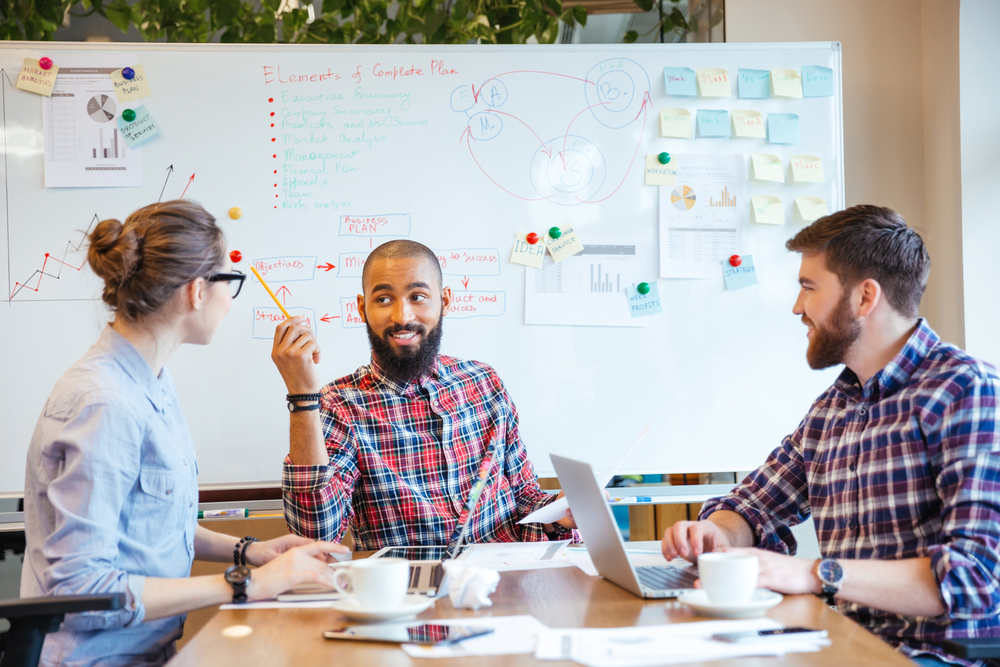 Multiethnic group of people in conference room, brainstorming property management marketing strategies.