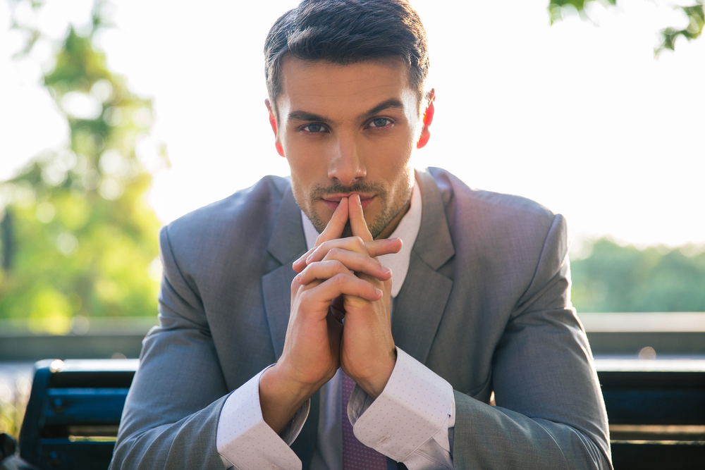 Portrait of a businessman sitting on the bench outdoors and thinking