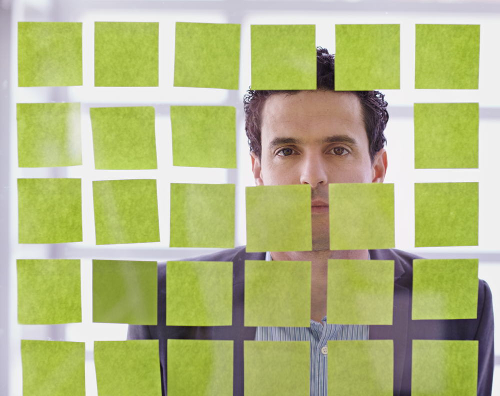 Portrait of a middle eastern business man behind sticky notes in bright glass office-1