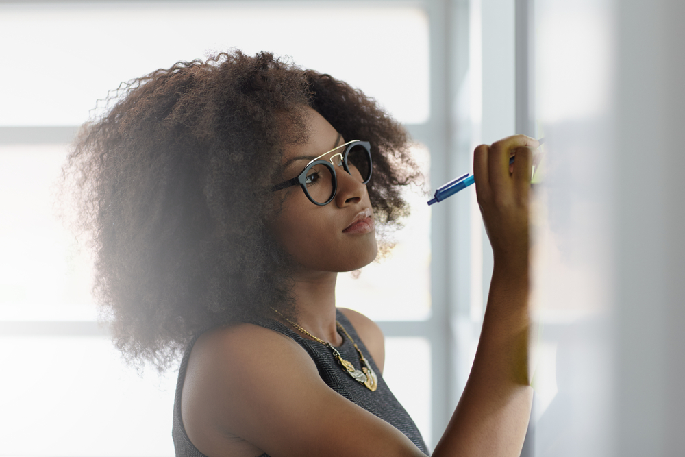 Portrait of a smiling business woman with an afro in bright glass office