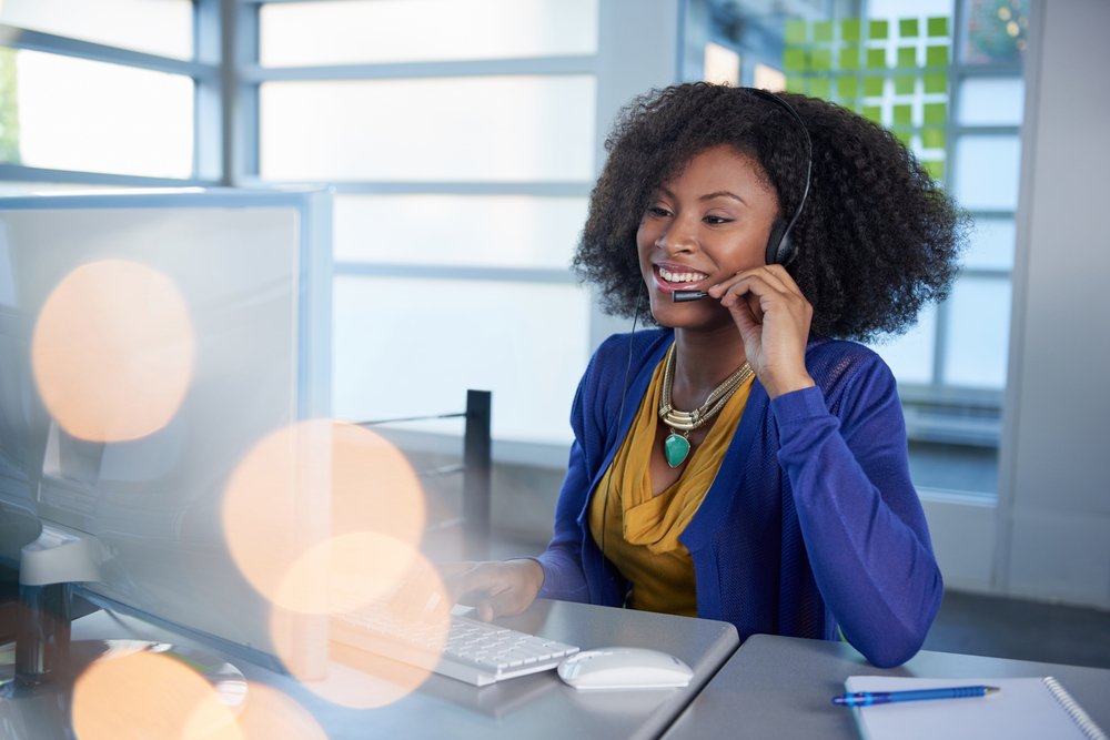 Portrait of a smiling customer service representative with an afro at the computer using headset-2