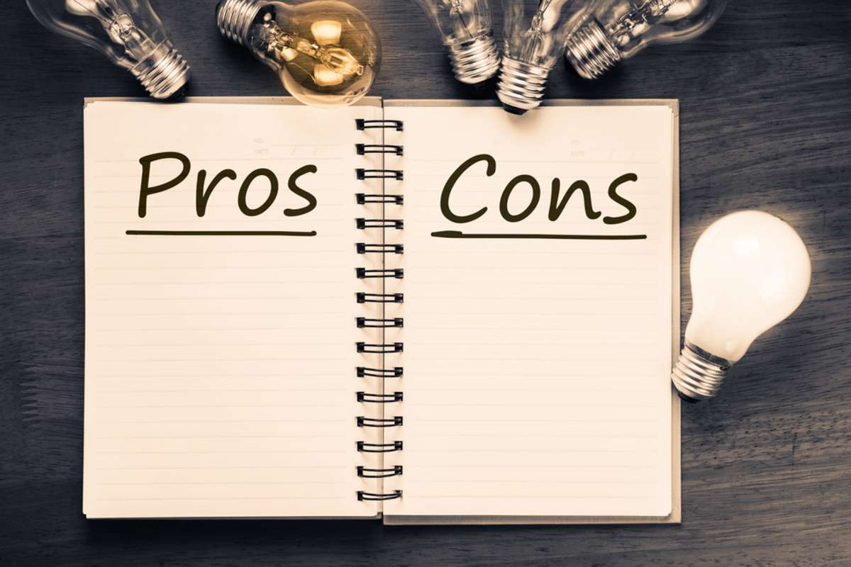 Pros and Cons text on notebook with many light bulbs