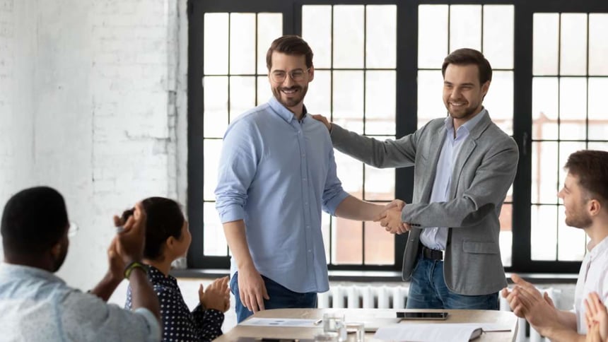 Proud boss encouraging and thanking happy employee for good job, shaking hand