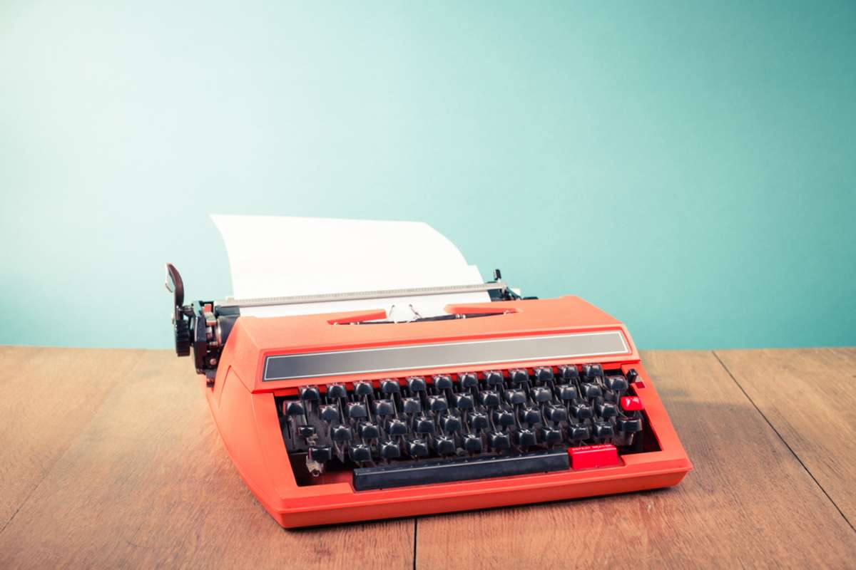 Retro red typewriter on a table, real estate blog concept