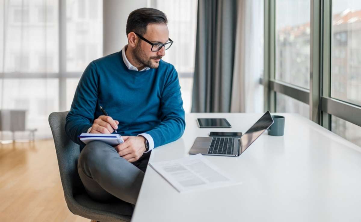 Serious male manager making notes in diary