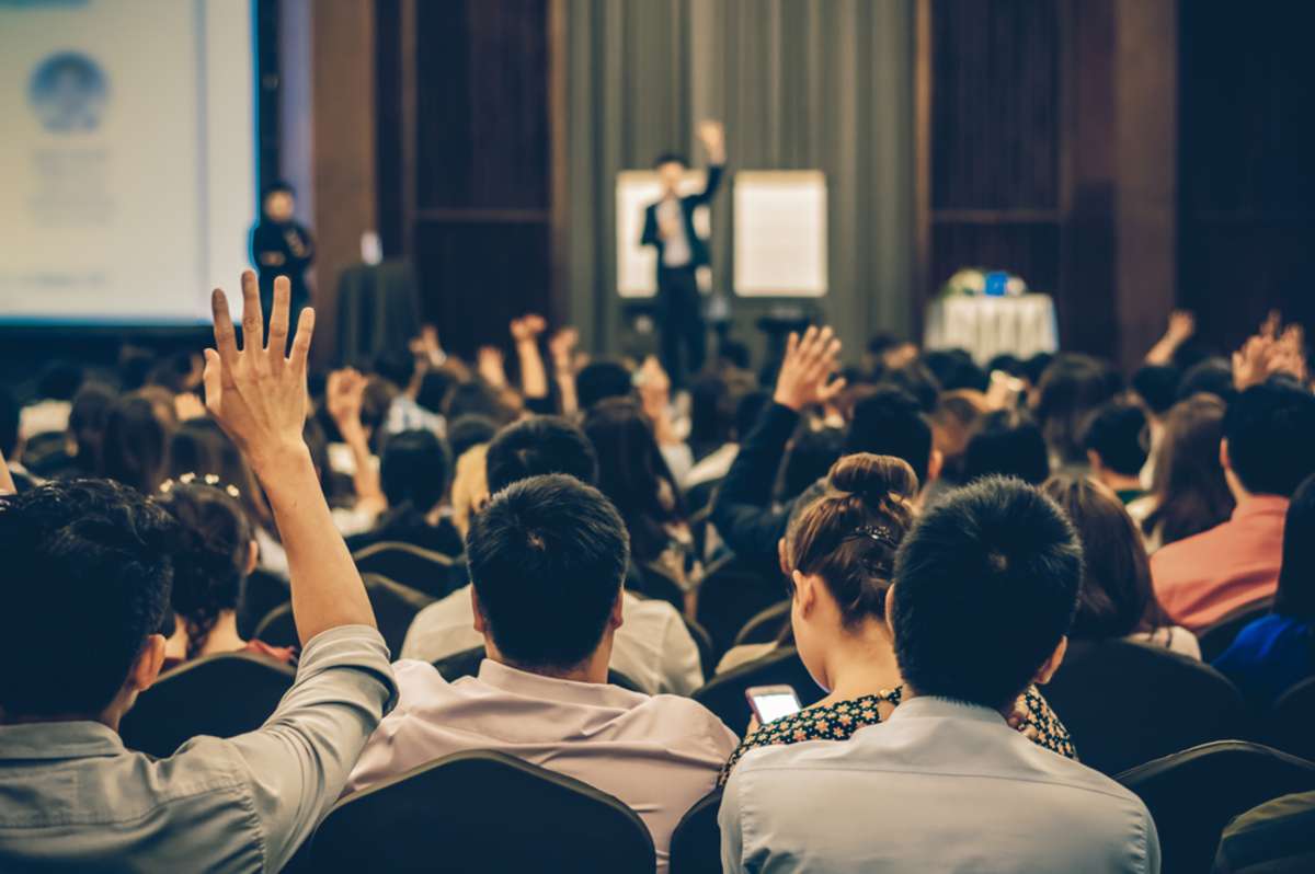 Speaker on the stage with Rear view of Audience in the conference hall or seminar meeting