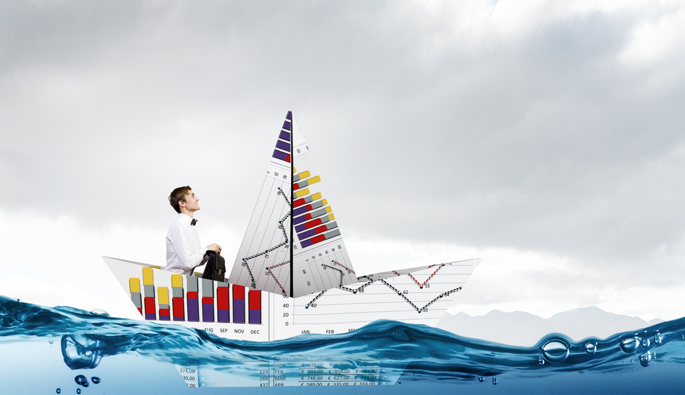 Successful businessman sailing on paper boat in financial sea-1