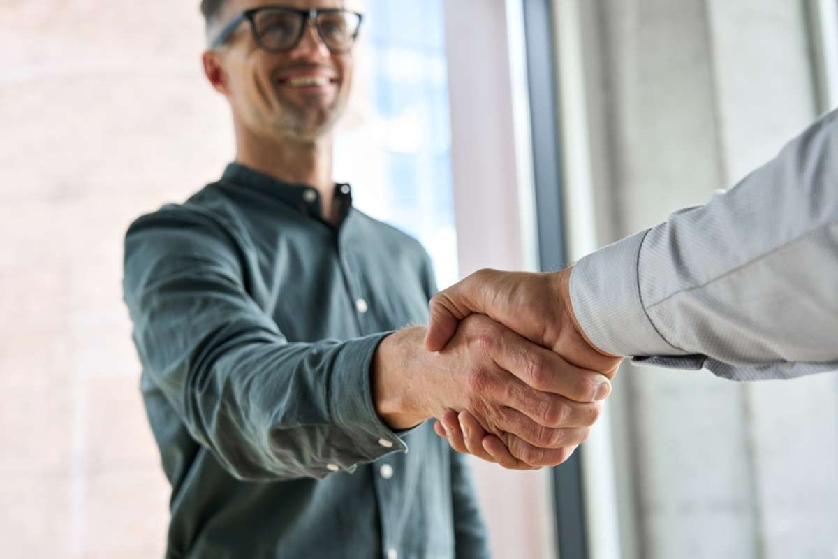 Two happy diverse professional business men executive leaders shaking hands at office meeting
