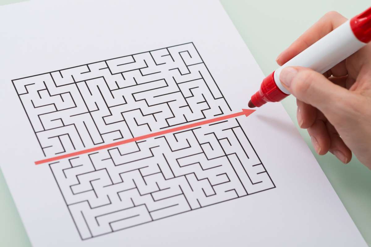 Woman Hand Drawing Straight Red Line Over Maze With Red Marker