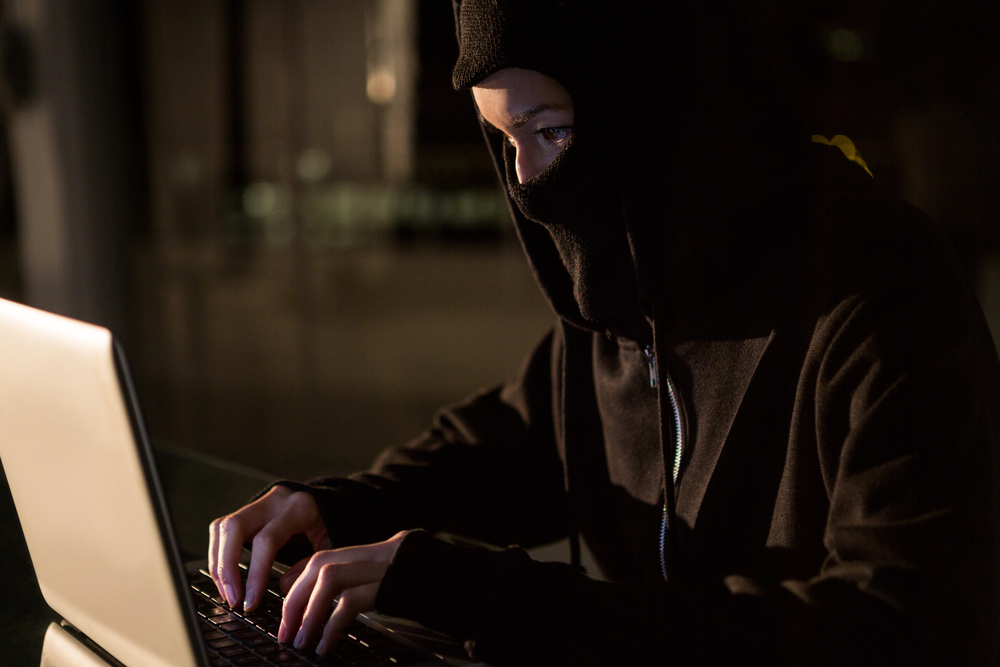 Woman in balaclava using laptop in the office