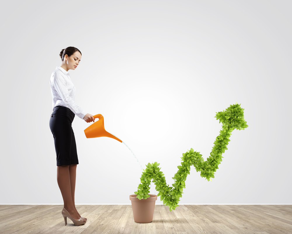 Young attractive businesswoman watering plant in pot with can