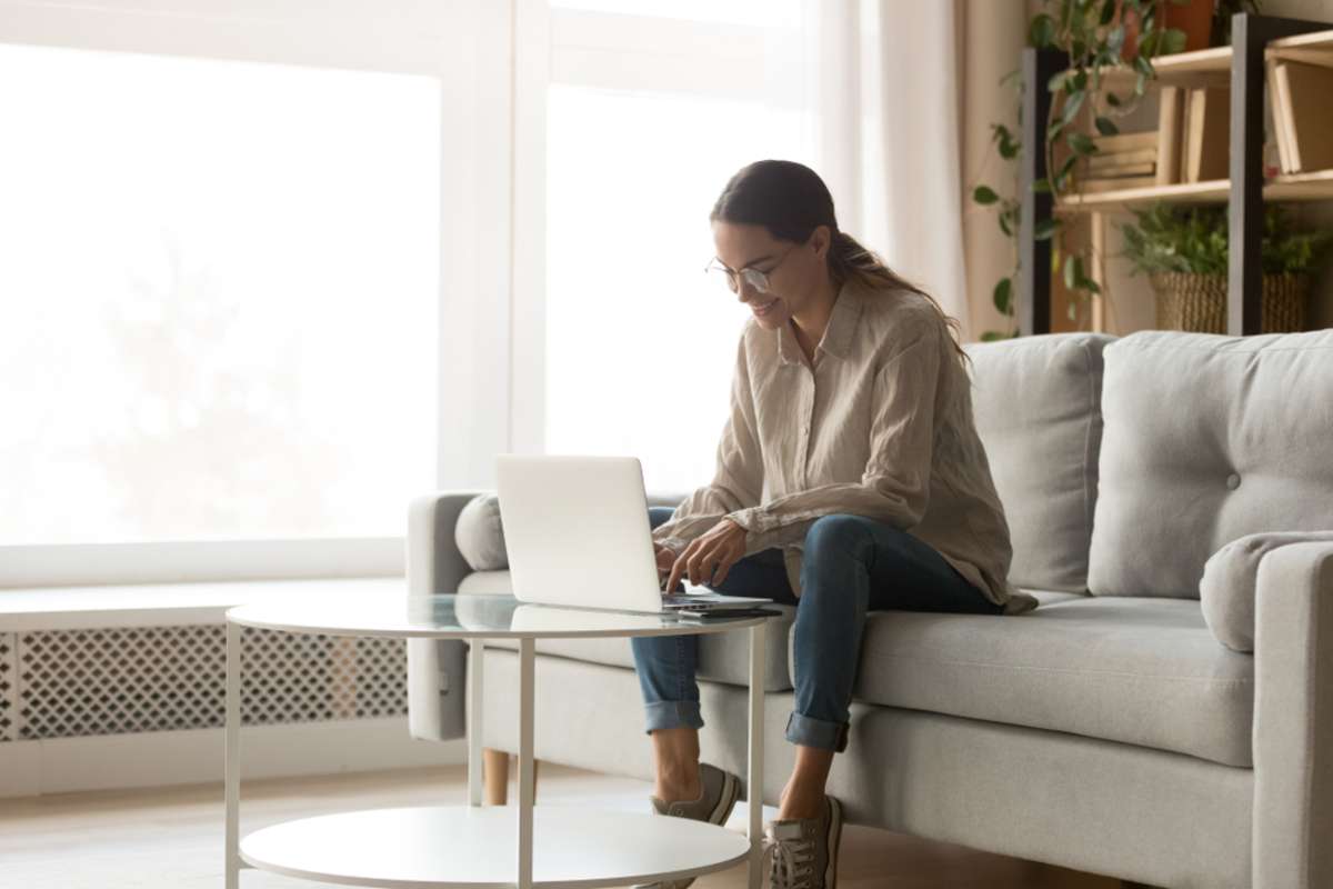 Young happy smiling mixed race woman working with computer in living room