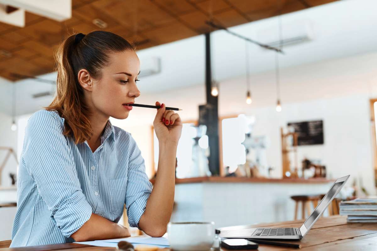 Young woman at a laptop thinking of real estate blog ideas