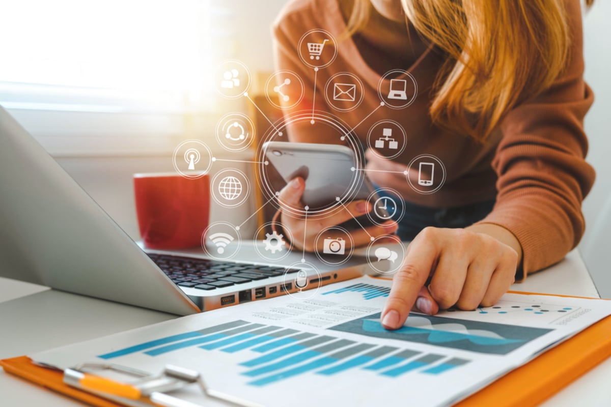 close up of businesswoman working with smart phone and laptop and digital tablet computer in modern office with virtual icon diagram