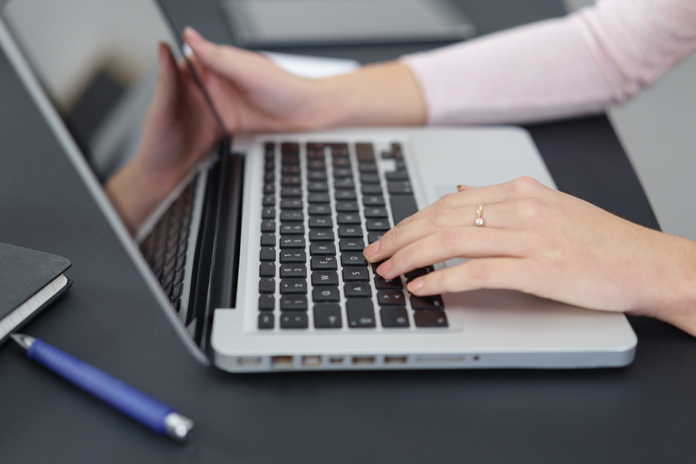 Close-up of womans hands working on her laptop, property management marketing concept. 