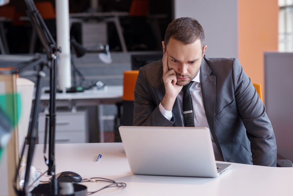 frustrated young business man working on laptop computer at office