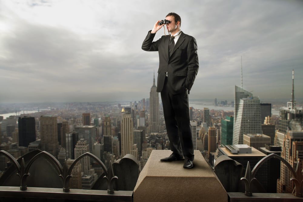 A businessman with binoculars looking to the distance, property management marketing concept. 