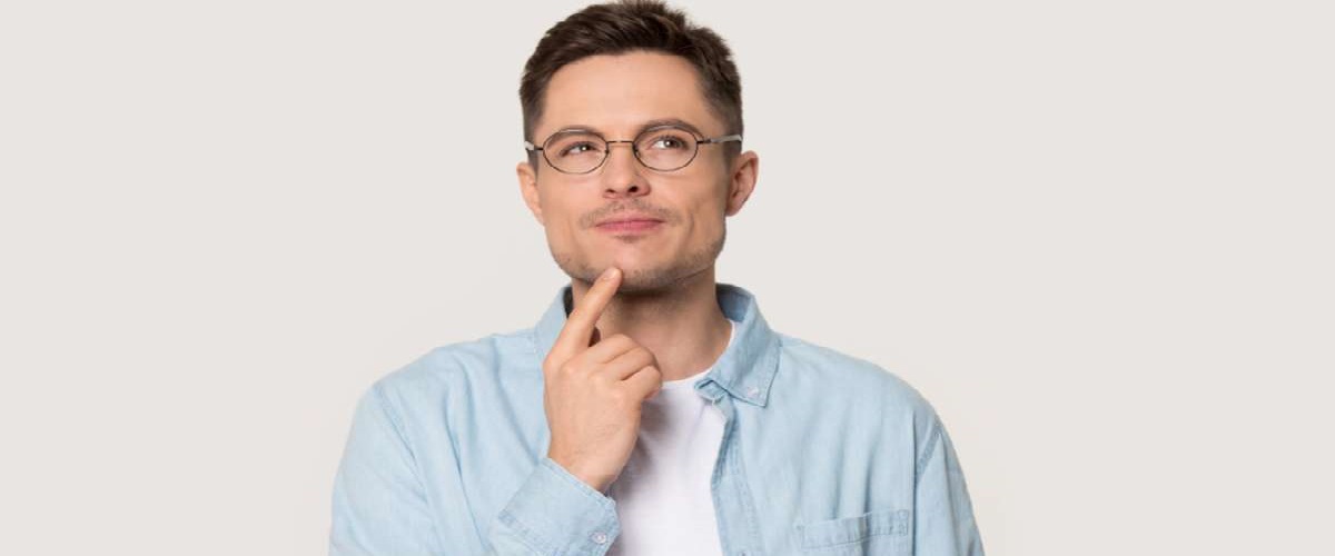 Thoughtful Caucasian young male in glasses touch chin with finger thinking or considering