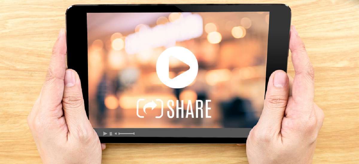 Hand holding tablet with Video sharing on screen on wood table 3